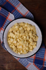 Bowl of cut sweet potato or yam on wooden table with kitchen towel. Top view. Nutricious tasty vegetarian food, local farmer harvest