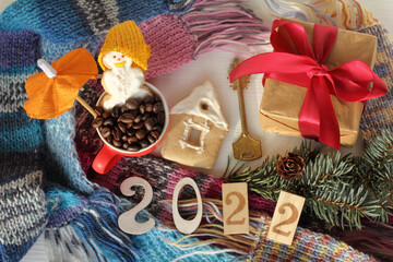gingerbread house, key, gift, cheerful snowman, fir branch against the background of a heap of multi-colored scarves, top view. home winter holidays 2022