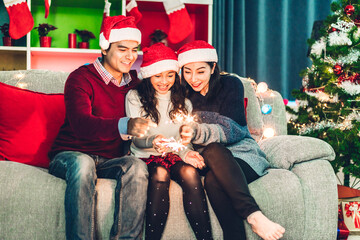 Portrait of happy asian family father and mother with daughter in santa hats having fun look at...