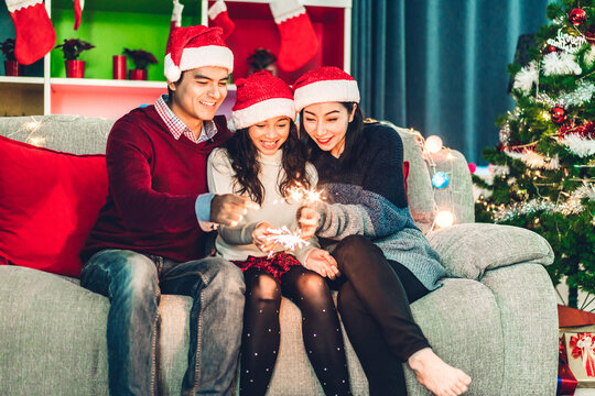 Portrait of happy asian family father and mother with daughter in santa hats having fun look at camera and enjoying spending time together in christmas time at home