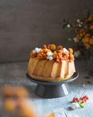 Whole citrus orange cake with flowers and berries on table, selective focus