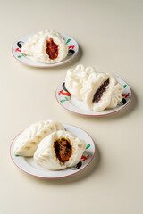 Delicious Baozi, Chinese steamed meat bun is ready to eat on serving plate and steamer. Baozi or Bakpao is a type of yeast-leavened filled bun in various Chinese cuisines. 