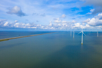 Fototapeta premium Drone photography of enormous windmills stand in the sea along a dutch sea. Fryslân wind farm, the largest inland wind farm in the world. Friesland, Afsluitdiijk, Ijsselmeer, Breezanddijk, Netherlands
