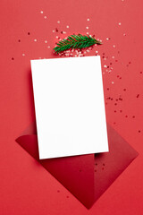 Christmas or New Year greeting card mockup with envelope and festive confetti decorations on red
