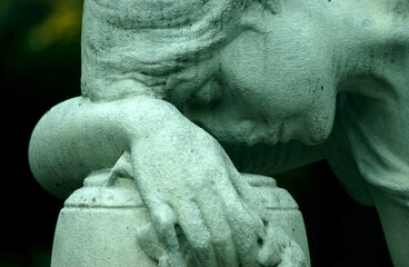An old, weathered sandstone sculpture of a grieving female angel.