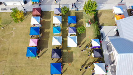Top view busy local people on sidewalk and grassy lawn shopping in colorful vendor tents at farmer market near Dallas, Texas, USA © trongnguyen