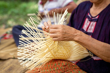 Cropped image of grandmother living in the countryside weaving bamboo making basket crafts at house. Thailand