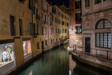 Fototapeta na wymiar Narrow canal between historic residential building illuminated with lamps at night