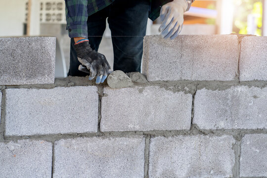 masonry worker make concrete wall by cement block and plaster at construction site