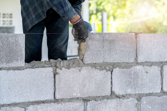 masonry worker make concrete wall by cement block and plaster at construction site