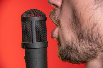 Singing Male Mouth In Front Of A Microphone On A Red Background. Broadcast, Radio and Podcasts....