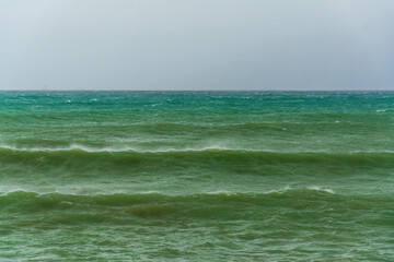 angry turquoise green color massive rip curl of a waves as it barrel rolls along the ocean. wild waves pound the coastline of chabahar in stormy day with cloudy sky close to coastline ,oman sea