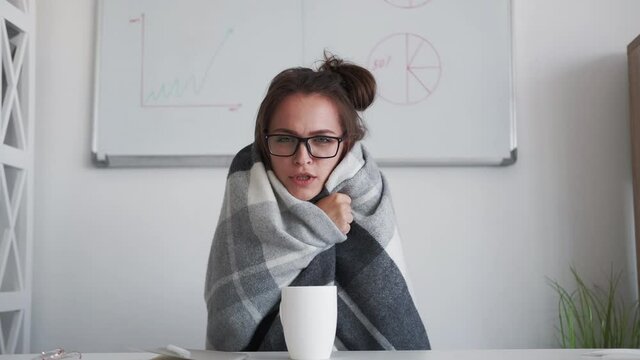 Sick office worker. Video call. Workaholic lifestyle. Responsible employee woman in plaid with fever feeling cold unwell working from home drinking hot tea.