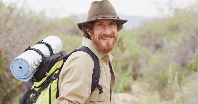 Portrait of smiling bearded caucasian male survivalist trekking through wilderness with backpack