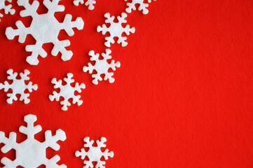 white snowflakes made of felt on a red background. Decoration for Christmas and New Year.