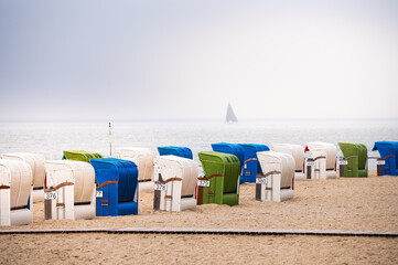 Green, blue and white strand baskets on the North Sea coast on the island of Föhr in hazy weather
