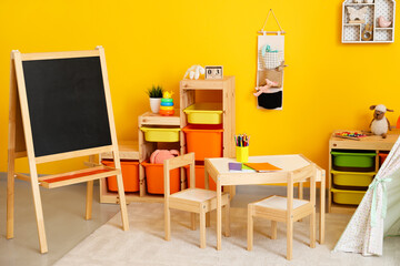 Stylish interior of modern children's room with table and chalkboard
