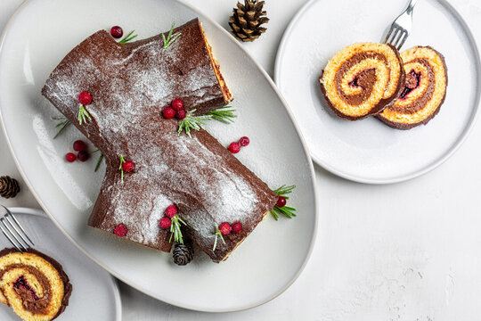 Yule log or Buche de Noel. Traditional Christmas cake. Sponge cake with chocolate cream, ganache, decorated with cranberries. Directly above, copy space.