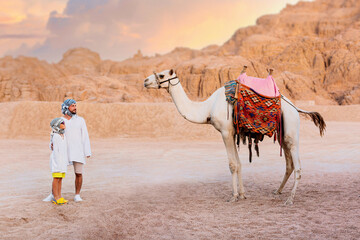 A man with his son, tourists, stand near a camel in the desert of Egypt