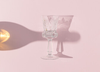 Champaign shadow and crystal glass on bright pink background. Minimal party concept. Creative celebration idea. Flat lay.