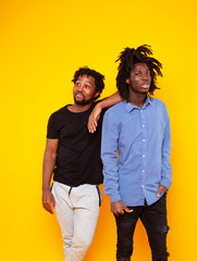 Fototapeta premium two african american guys posing cheerful together on yellow background, lifestyle people concept