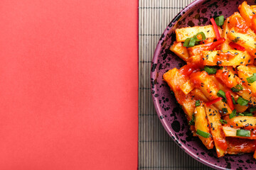 Plate with honey chilli potato on color background