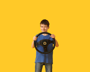 Little boy with steering wheel on color background