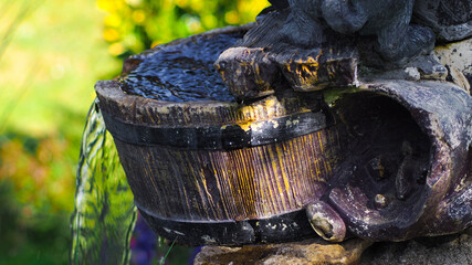 Vue rapprochée d'une cuve en bois, par laquelle s'écoule l'eau d'une fontaine, dans un bassin