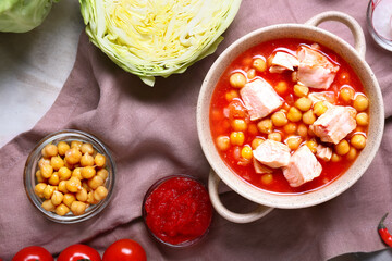 Delicious pozole soup in pot and ingredients on table
