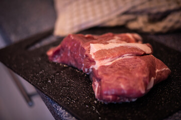a piece of meat, pork meat on a cutting board, raw red meat, fresh meat on the kitchen table