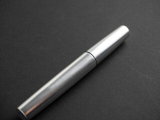 close-up of a closed mascara of silver color on a black background. The concept of cosmetics for women
