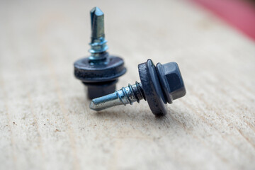 Roofing screws painted gray on a wooden background. Selective focus