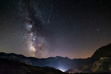 the Milky way galaxy and stars over the Italian French Alps. Night sky on majestic snowcapped mountains and glaciers. Meteor shower on the right