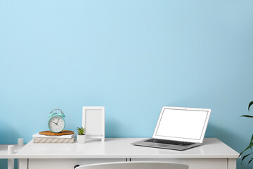 Stylish workplace with alarm clock and laptop in interior of room