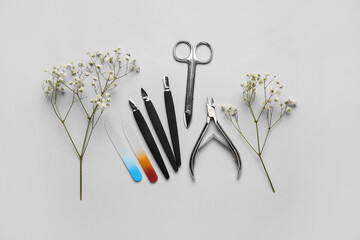 Manicure equipment and flowers on light background