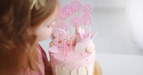 cute baby girl blowing the candlles on birthday cake. three years old