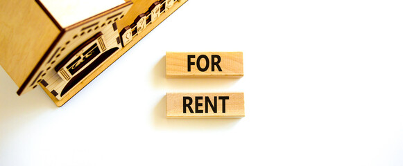 House for rent symbol. Concept words 'For rent' on wooden blocks near miniature house. Beautiful white background, copy space. Business and house for rent concept.