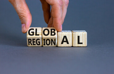 Regional or global symbol. Businessman turns wooden cubes and changes the word 'regional' to 'global'. Beautiful grey table, grey background. Business and regional or global concept. Copy space. - obrazy, fototapety, plakaty