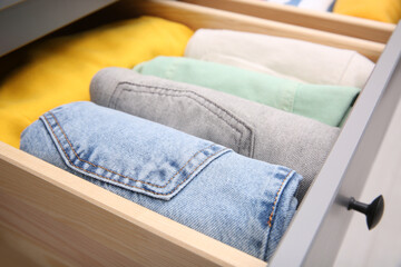 Fototapeta na wymiar Open drawer with folded clothes indoors, closeup. Vertical storage
