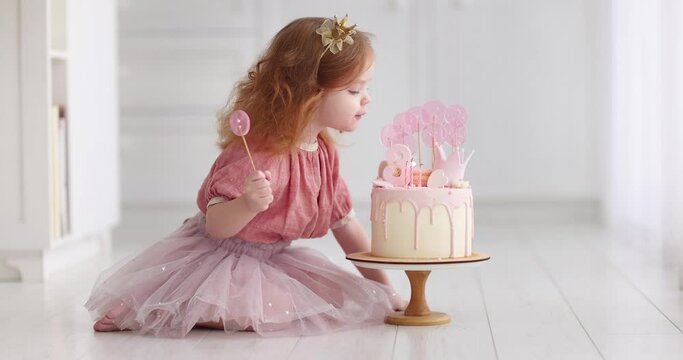 cute baby girl blowing the candles on birthday cake. three years old child