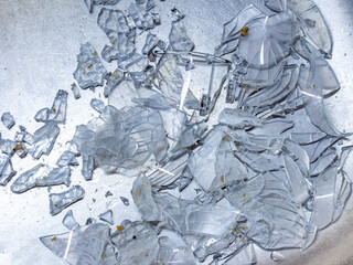 a lot of shards of glassware in a metal sink after careless dishwashing