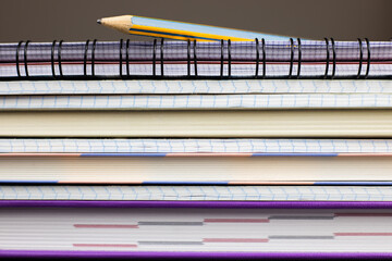 Stack of colorful notebooks with pencil on top of it. Background for learnin concept.