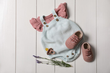 Children's shoes, clothes, pacifier and lavender on white wooden table