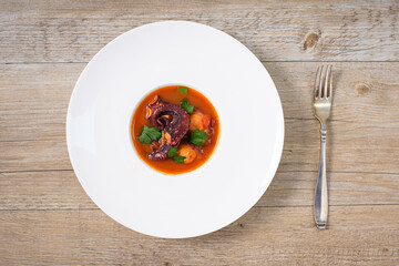 Plate on a table with braised octopus in tomato