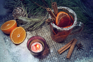 Christmas hot mulled wine with a slice of orange and spices. A glass cup with a hot traditional drink on a snowy background in festive decorations. Evening mood and decoration 