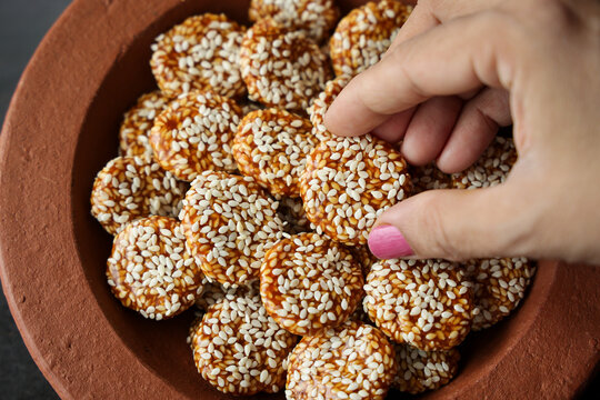 Revdi revri til gud revdi rewari sesame winter food woman hand serving Indian festival food snack sweet Lohri Makar Sankranti Pongal Diwali harvest festival Tamil Nadu festival Punjab North India 