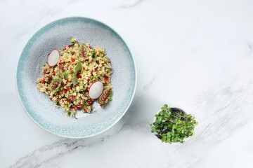 bulgur with vegetables red pepper and radish on light marble background.