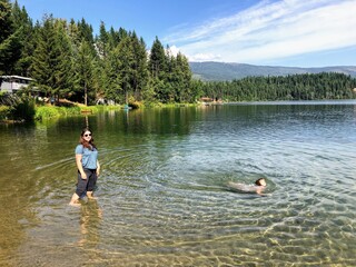 A mother and daughter enjoying swimming and wading in dutch lake with beautiful clear water surrounded by forest, on a lovely summer day in Clearwater, British Columbia, Canada