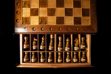 Dark chess pieces lie in a box. A puzzle game with tricky combinations that requires planning and thinking.