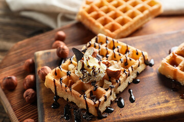 Board of tasty Belgian Waffles with cream and hazelnut on wooden background